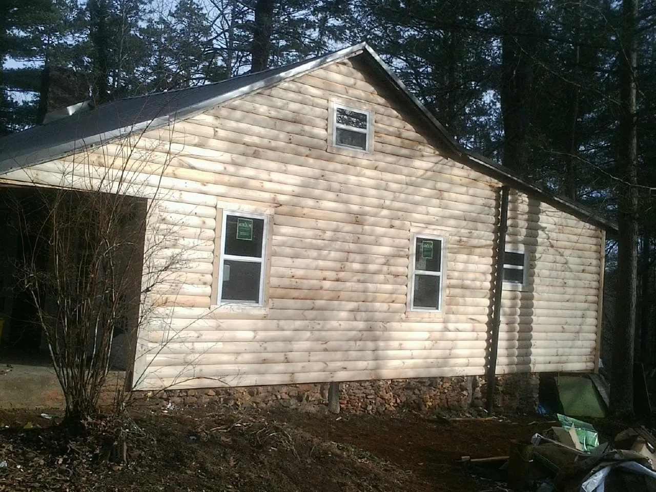 New log siding and dark metal roofing on a gable end in Munnsville