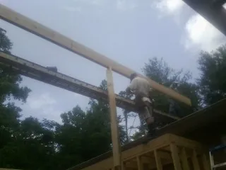 Carpenter setting a ridge beam over a new addition frame — Ice Dam Removal by Roofing Brothers in Munnsville