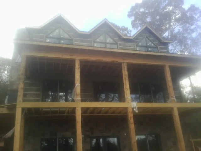 Dormers and porch framing on a large log home under construction — Roof Coating work by our crew in Munnsville