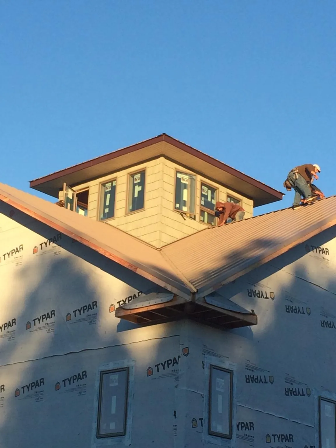 Roofers working around a rooftop cupola on a new metal roof at sunset — Roof Waterproofing in Munnsville by Roofing Brothers